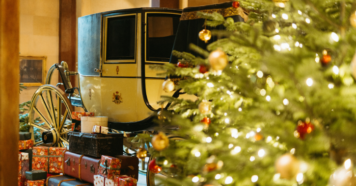 Christmas presents and Christmas tree on display next to an historic carriage at Raby Castle.